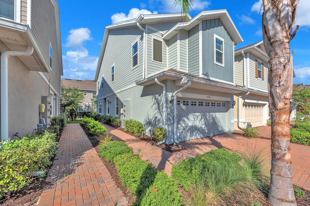 A two-story house with light green siding, a brick walkway, and a two-car garage — 5741 SPOTTED HARRIER WAY, LITHIA, FL