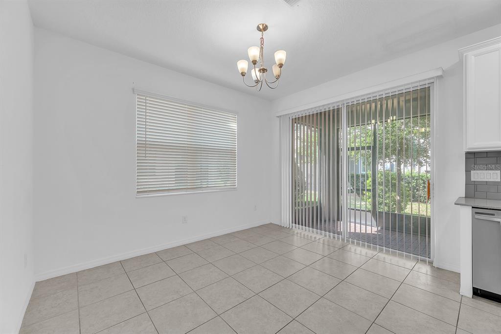 A dining area with tile flooring, a chandelier, a window with blinds, and sliding glass doors — 5741 SPOTTED HARRIER WAY, LITHIA, FL