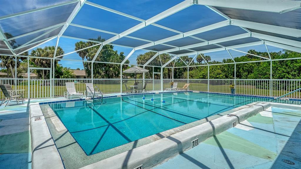 A screened-in swimming pool with a surrounding patio and lounge chairs under a blue sky — 2902 CAPTIVA GARDENS DRIVE UNIT 3, SARASOTA, FL