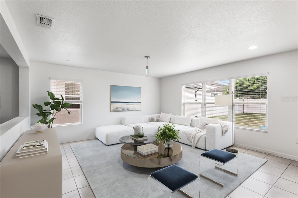 A bright living room features a white sectional sofa, a round coffee table, and tile flooring — 11309 BRIGHTON KNOLL LOOP, RIVERVIEW, FL
