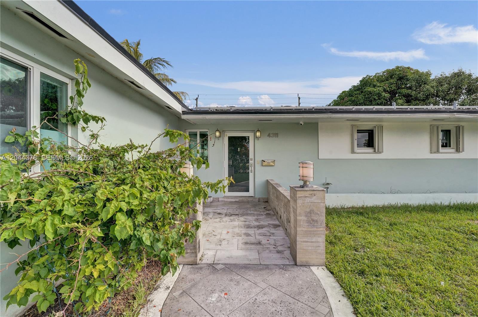 The exterior of a single-story house features a paved walkway leading to a glass front door — 4311 Hayes St, Hollywood FL 33021, HOLLYWOOD, FL