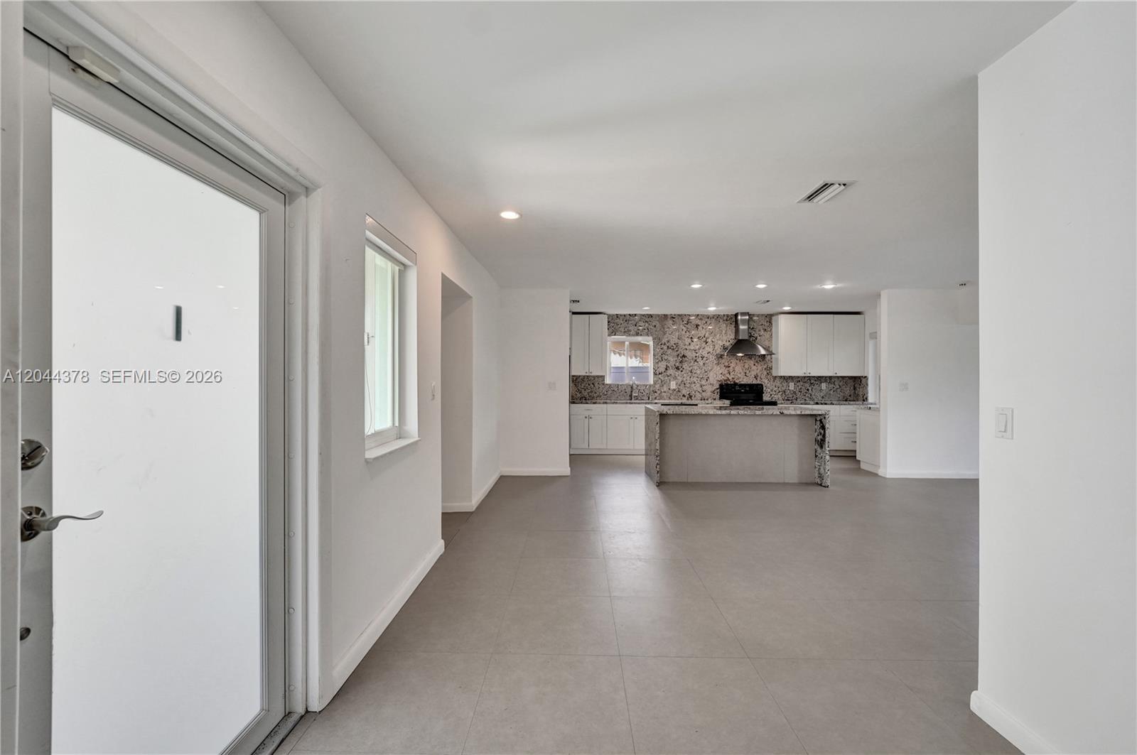 An open-concept kitchen features white cabinets, granite countertops, and light gray tile flooring — 4311 Hayes St, Hollywood FL 33021, HOLLYWOOD, FL