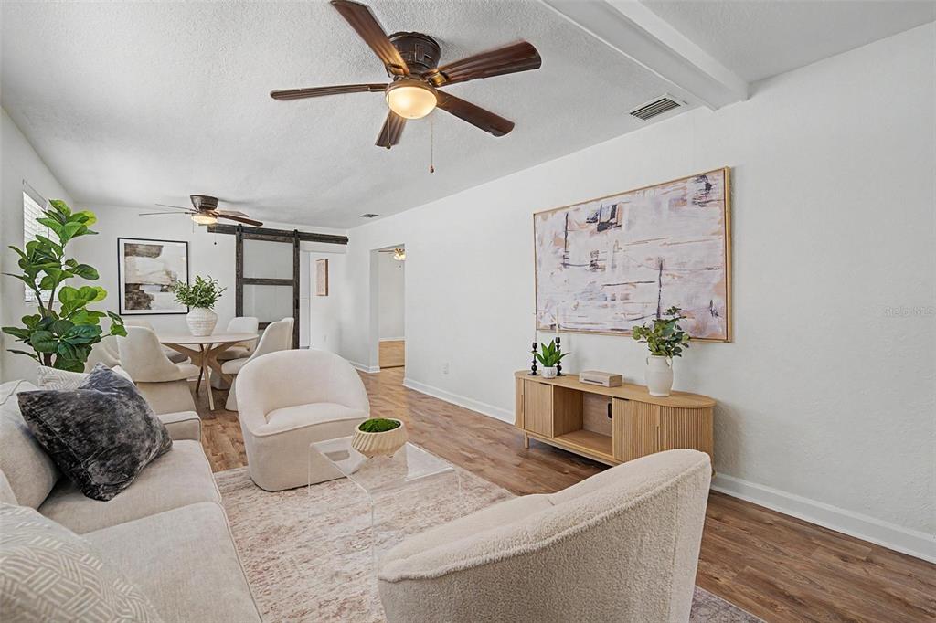 A living room with white walls, wood-look flooring, a ceiling fan, and modern neutral furniture — 3913 N LYNN AVENUE, TAMPA, FL