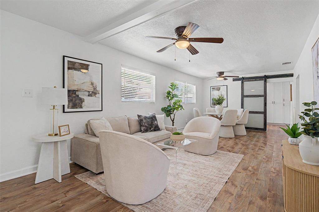 A living and dining area features white walls, wood-look flooring, and two ceiling fans — 3913 N LYNN AVENUE, TAMPA, FL