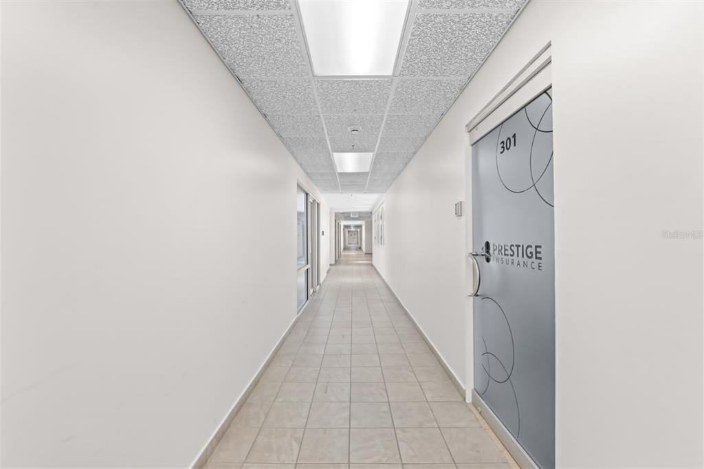 A long, narrow office hallway features white walls, tiled flooring, and a glass-fronted office door — 100 CENTRO INTERNACIONAL DE MERCADEO UNIT 305, GUAYNABO, PR