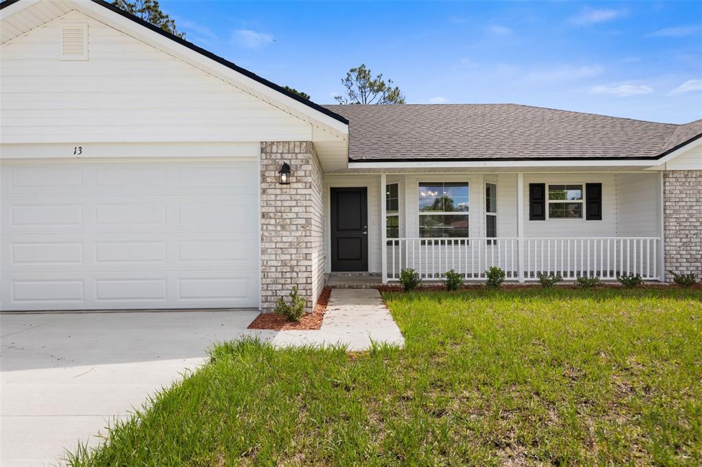The exterior of a single-story house features white siding, brick accents, and a front porch — 2 ULMACEAL PATH, PALM COAST, FL