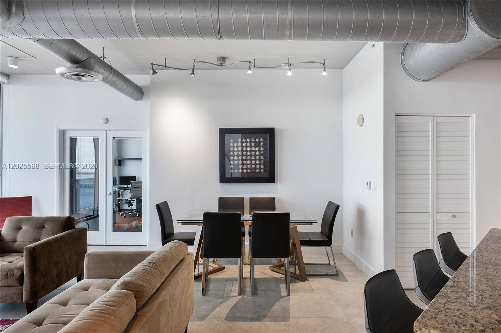 A dining area with a glass table and chairs sits beneath exposed industrial ductwork — 700 NE 25th St # 1902, Miami FL 33137, MIAMI, FL