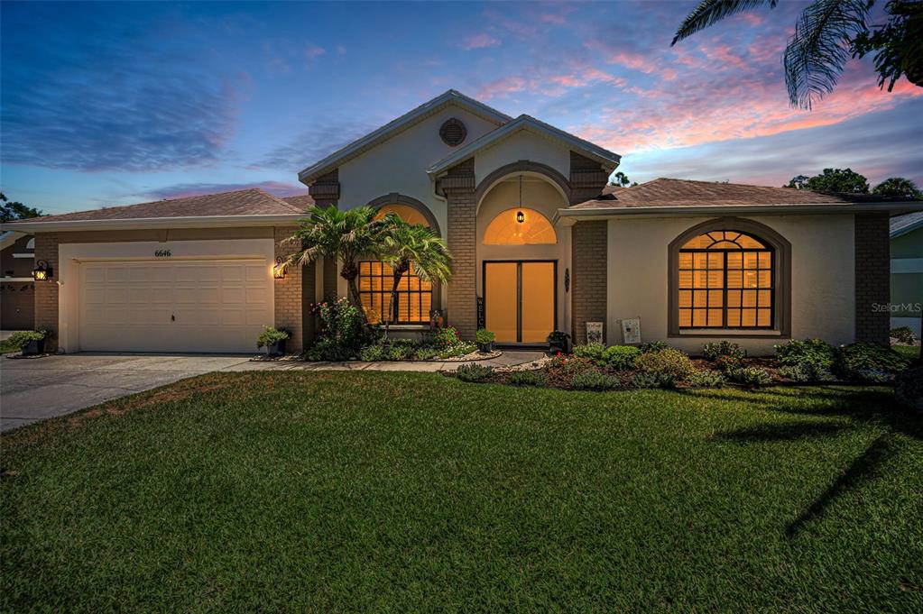 A single-story house with a two-car garage, arched windows, and a landscaped front yard — 6646 GARDEN PALM COURT, NEW PORT RICHEY, FL