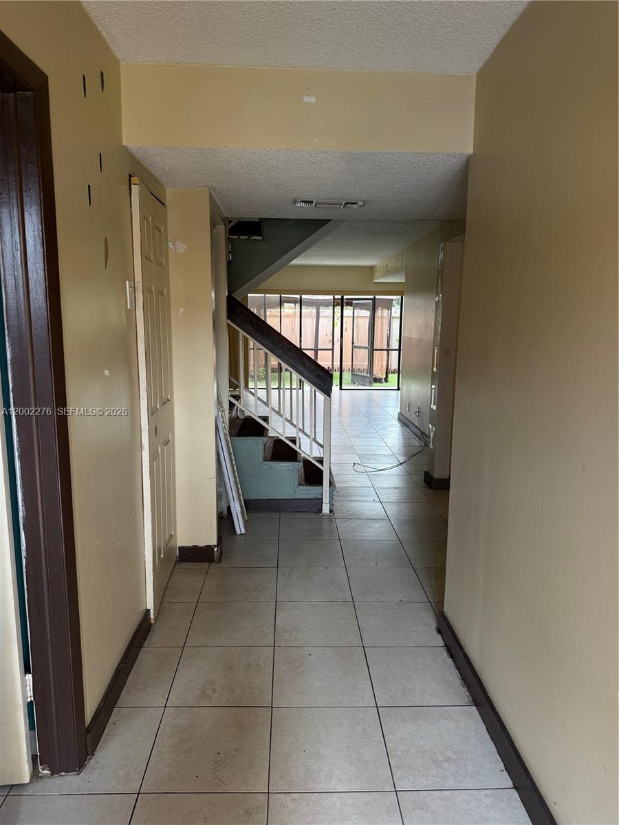 A hallway with tile flooring leads to a staircase and a view of the backyard — 8024 NW 27th Ct, Sunrise FL 33322, SUNRISE, FL