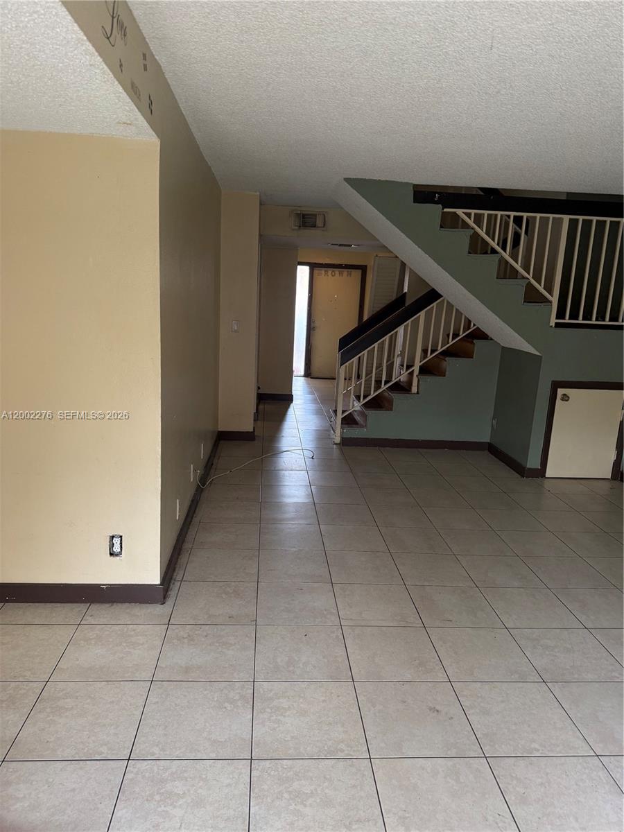 An interior view shows a tiled living area with a staircase and a doorway — 8024 NW 27th Ct, Sunrise FL 33322, SUNRISE, FL