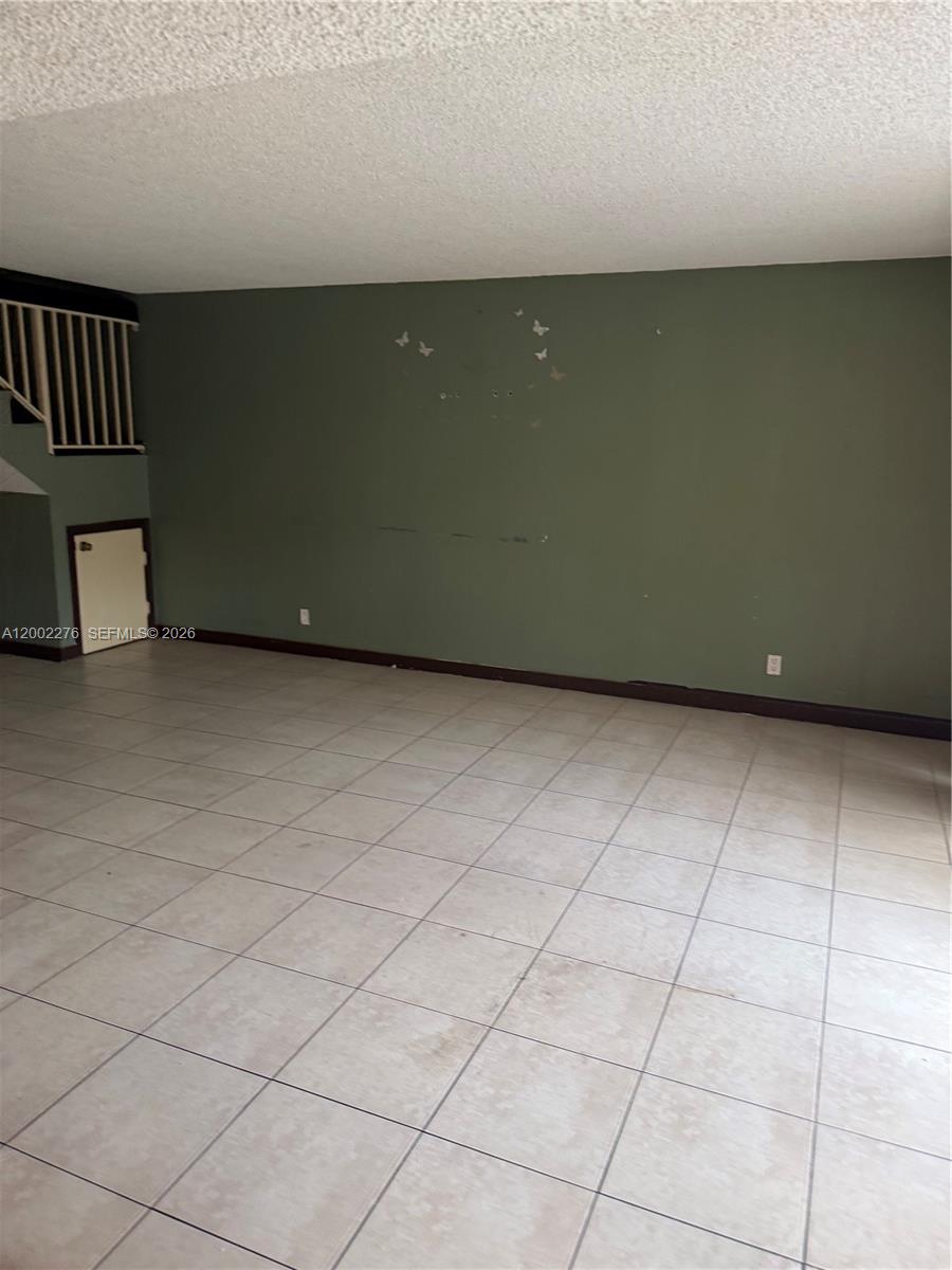 An empty room features olive green walls, tile flooring, and a small under-stair storage door — 8024 NW 27th Ct, Sunrise FL 33322, SUNRISE, FL