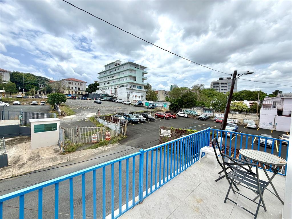 A balcony with a blue railing overlooks a parking lot and surrounding city buildings — 1410 EDUARDO GEORGETTI, SAN JUAN, PR