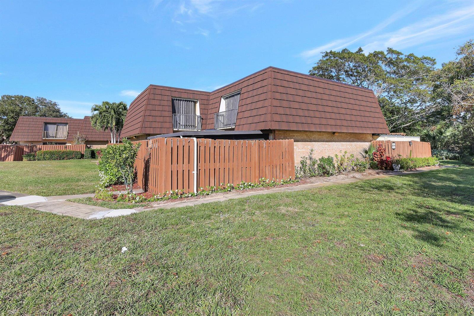 A two-story townhouse with a brown mansard roof and a wooden privacy fence — 5852 SE Riverboat Drive # 321, Stuart FL 34997, STUART, FL
