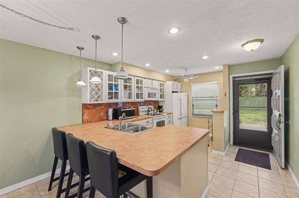 A living room with tile flooring, green walls, and an open kitchen with bar seating — 4800 LAKE VILLA DRIVE, CLEARWATER, FL
