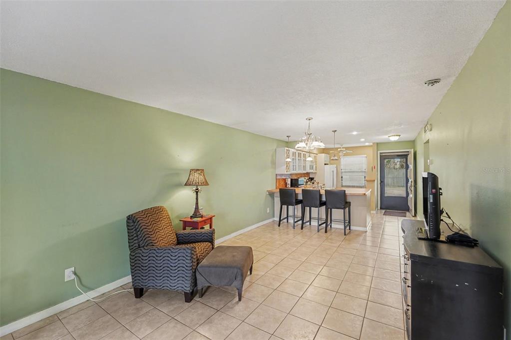 A kitchen features white cabinets, a red stone backsplash, laminate countertops, and white appliances — 4800 LAKE VILLA DRIVE, CLEARWATER, FL