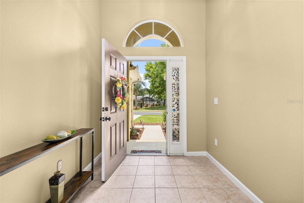 A kitchen with wood cabinets and a breakfast bar opens into a living area — 3108 MERLOT WAY, CLERMONT, FL