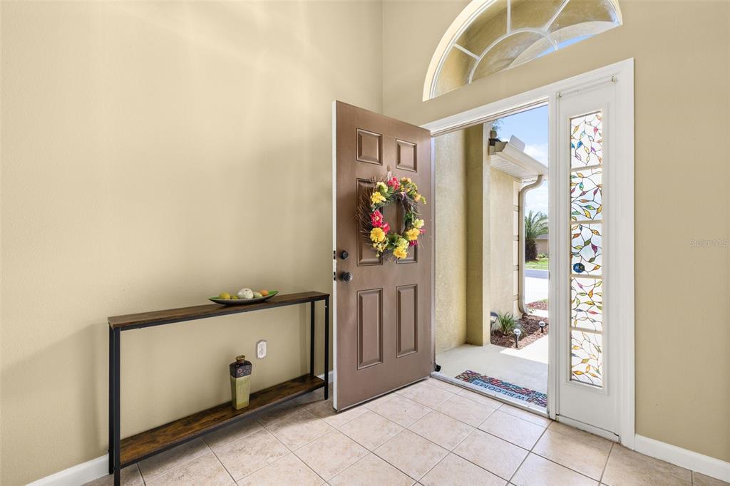 An entryway with light wood flooring, a console table, and an open front door — 3108 MERLOT WAY, CLERMONT, FL