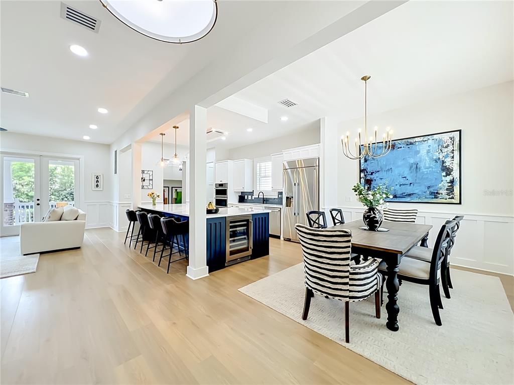 An open-concept kitchen and dining area features a blue island, wood floors, and striped chairs — 217 W BAY STREET, WINTER GARDEN, FL