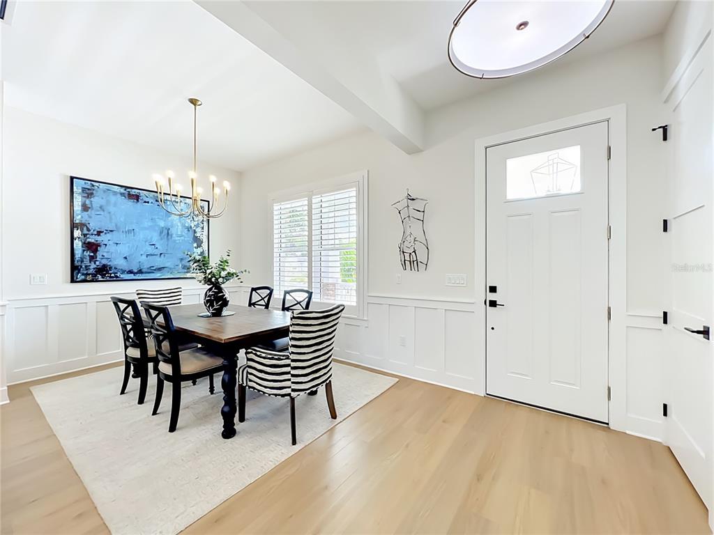 A dining area with a wooden table, striped chairs, and white wainscoting near an entryway — 217 W BAY STREET, WINTER GARDEN, FL