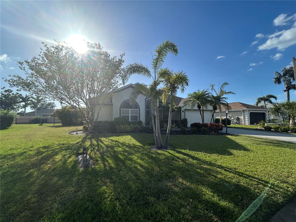 A single-story house with a lawn, palm trees, and a driveway under a sunny sky — 7448 39TH COURT E, SARASOTA, FL