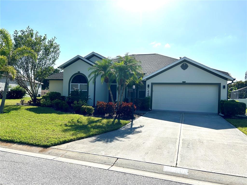 A single-story house with a two-car garage, palm trees, and a concrete driveway — 7448 39TH COURT E, SARASOTA, FL