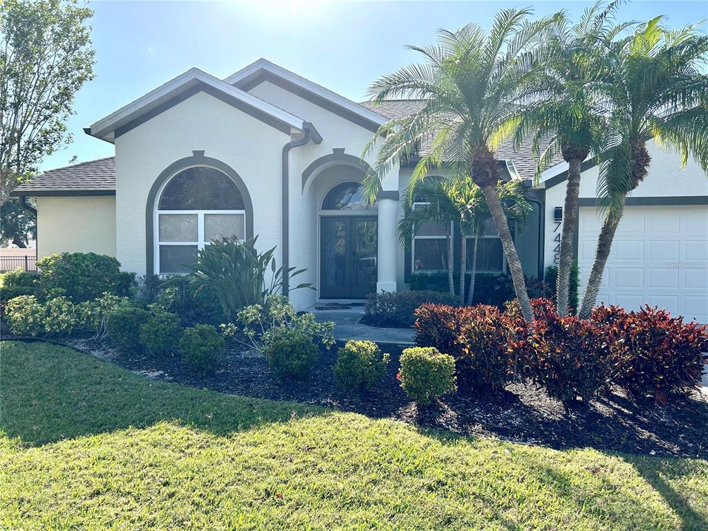 A single-story house with a white stucco exterior, arched windows, and a palm-lined front yard — 7448 39TH COURT E, SARASOTA, FL