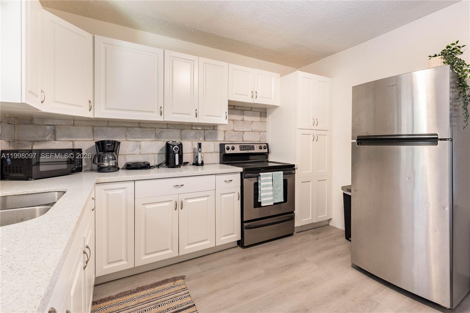 A kitchen features white cabinets, stainless steel appliances, and a gray cinder block backsplash — 20 SE 13th Ter # 2, Dania Beach FL 33004, DANIA BEACH, FL