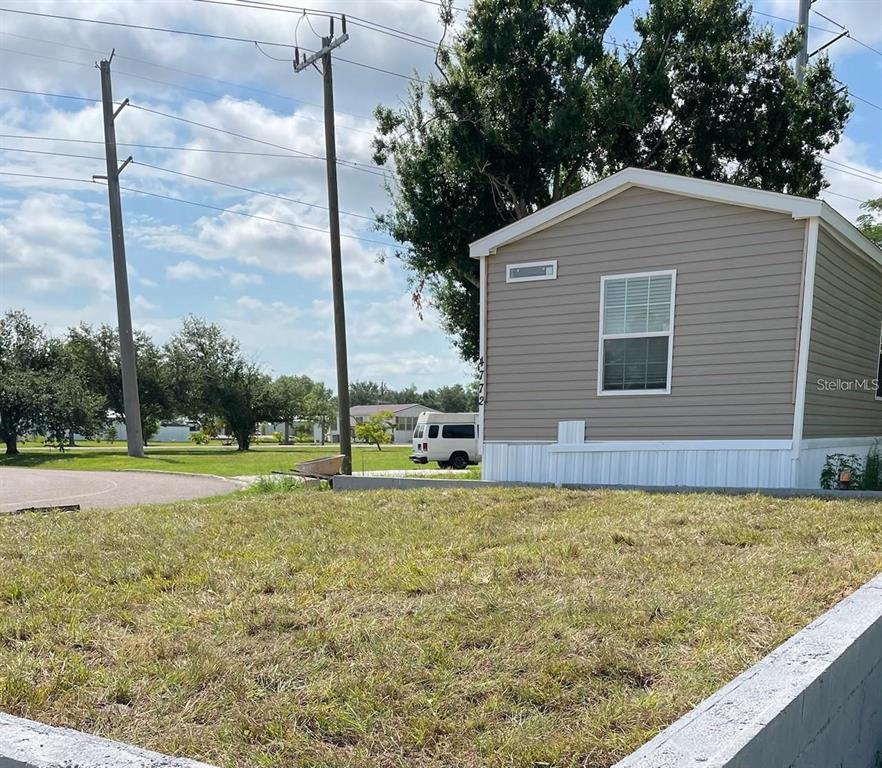 A tan mobile home sits on a grassy lot next to utility poles — 4772 DUNCAN ROAD, PUNTA GORDA, FL