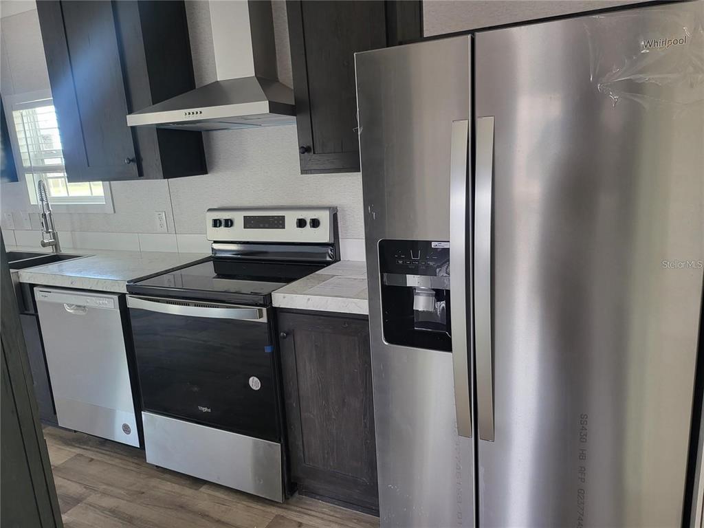 A kitchen features dark cabinets, stainless steel appliances, and light countertops — 4772 DUNCAN ROAD, PUNTA GORDA, FL
