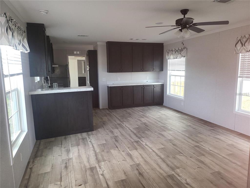 A kitchen and dining area with dark cabinetry, white countertops, and light wood-look flooring — 4772 DUNCAN ROAD, PUNTA GORDA, FL