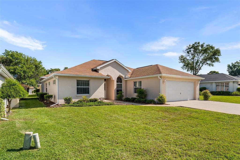 A single-story beige stucco house with a two-car garage and a brown shingled roof — 11295 SW 73RD CIRCLE, OCALA, FL