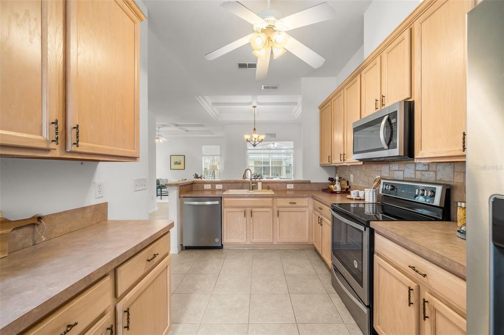 A kitchen features light wood cabinets, stainless steel appliances, and a tile floor — 11295 SW 73RD CIRCLE, OCALA, FL
