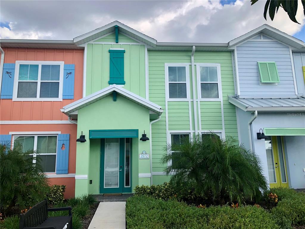A multi-story townhouse exterior features pastel-colored siding, blue shutters, and a central front entrance — 2972 ON THE ROCKS POINT, KISSIMMEE, FL