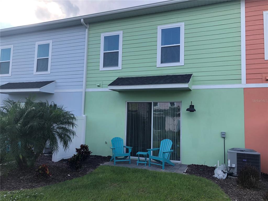 The exterior of a green townhouse features a small patio with two blue Adirondack chairs — 2972 ON THE ROCKS POINT, KISSIMMEE, FL