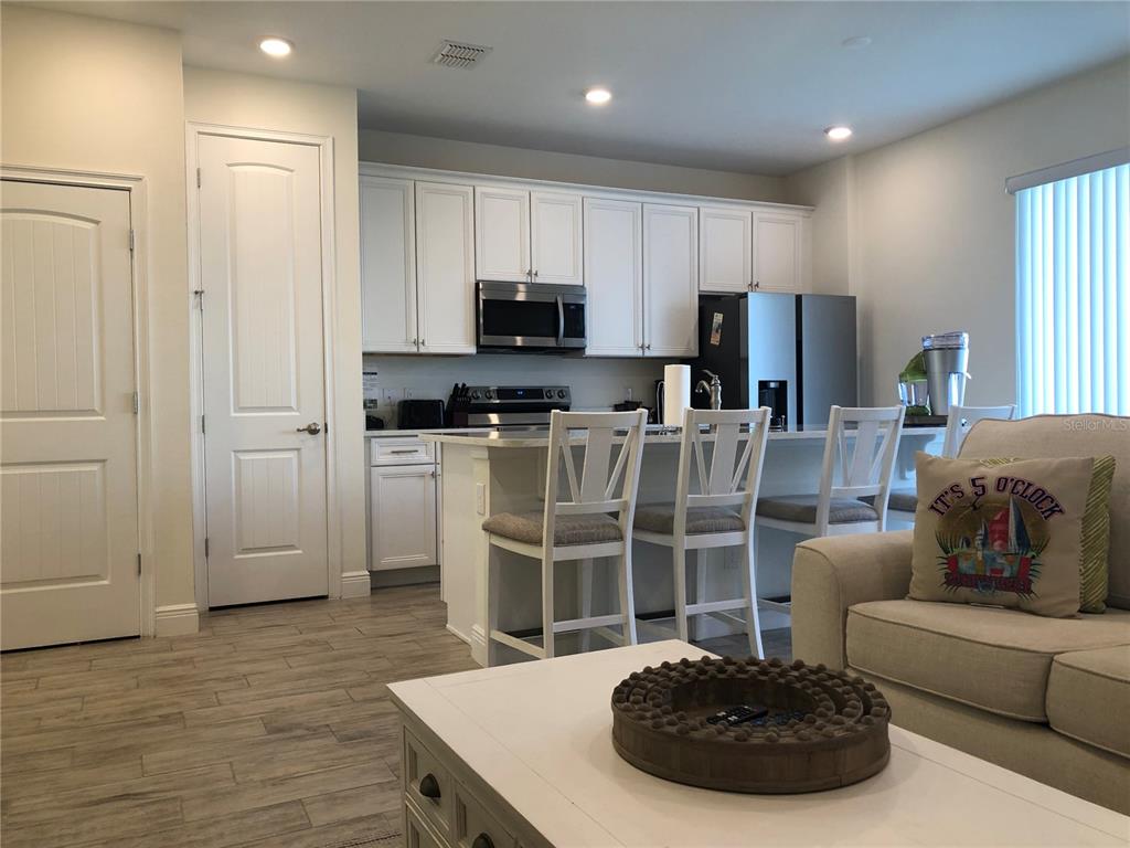A kitchen with white cabinets, stainless steel appliances, and an island with three bar stools — 2972 ON THE ROCKS POINT, KISSIMMEE, FL