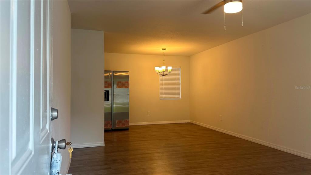 An interior view shows a room with wood-look flooring, a chandelier, and a stainless refrigerator — 5920 NW 65TH STREET, OCALA, FL
