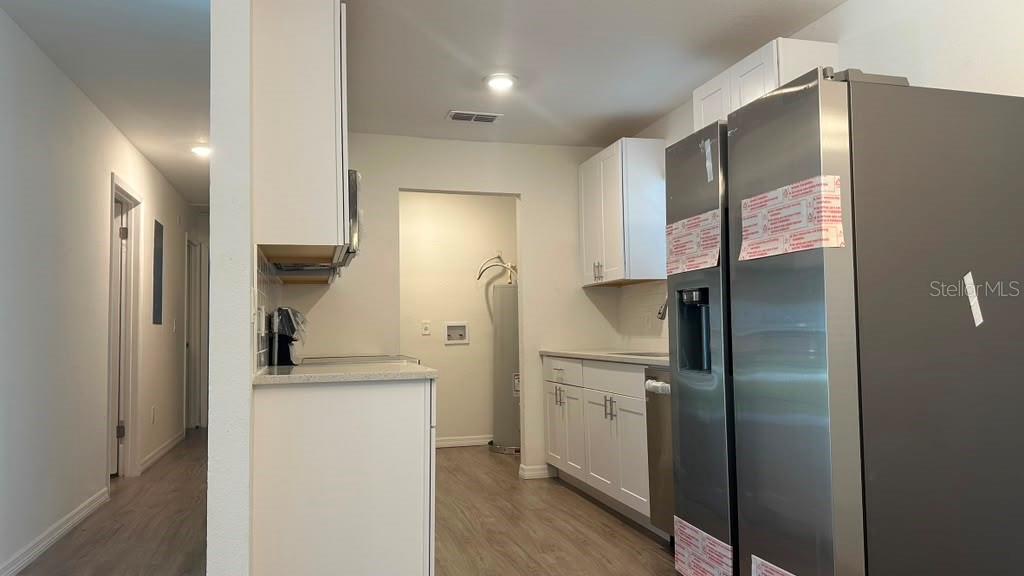 A kitchen features white cabinets, stainless steel appliances, and light wood-look flooring — 5920 NW 65TH STREET, OCALA, FL