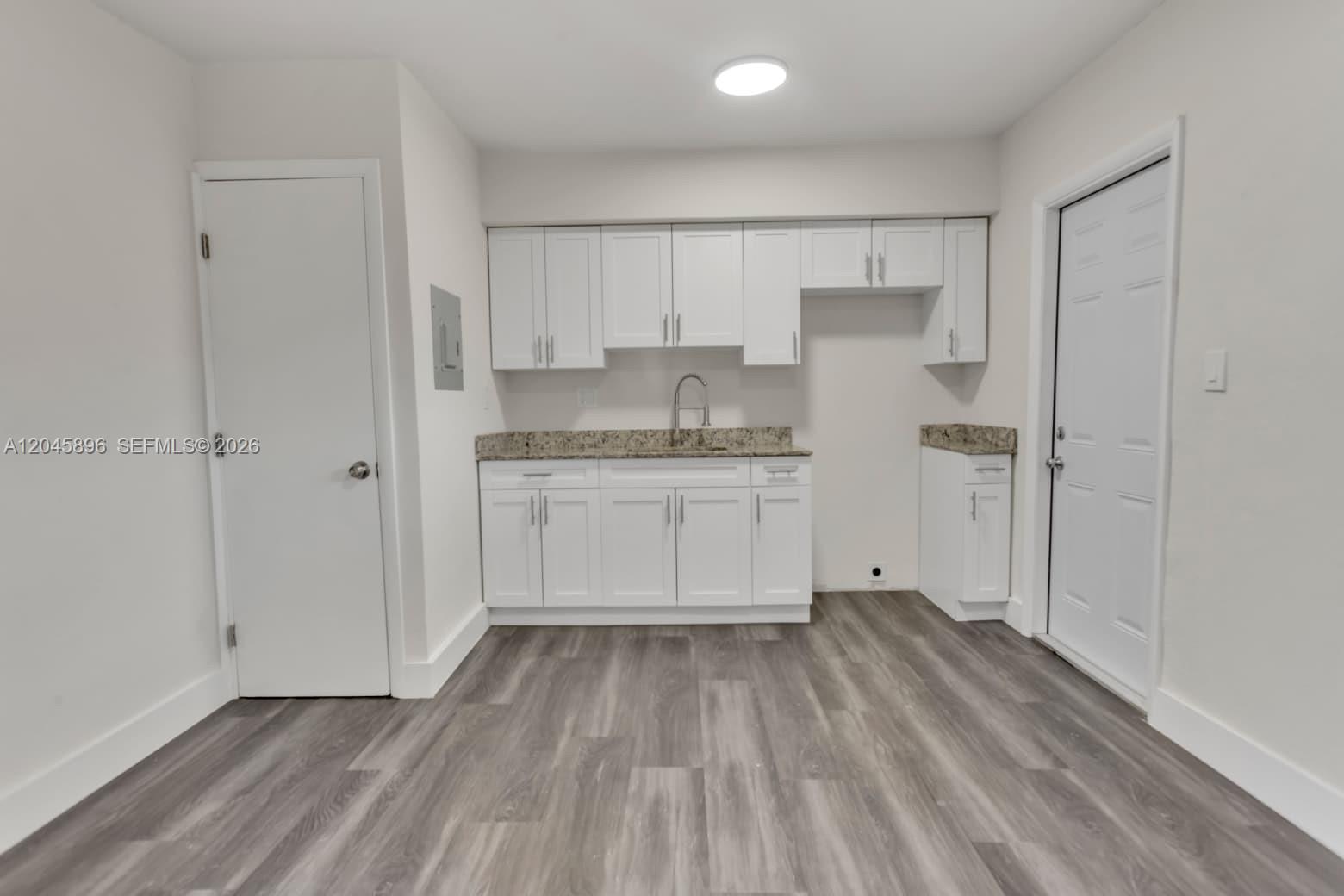 This kitchen features white cabinets, granite countertops, and wood-look flooring — 1430 NW 2nd Ave # 2, Florida City FL 33034, FLORIDA CITY, FL
