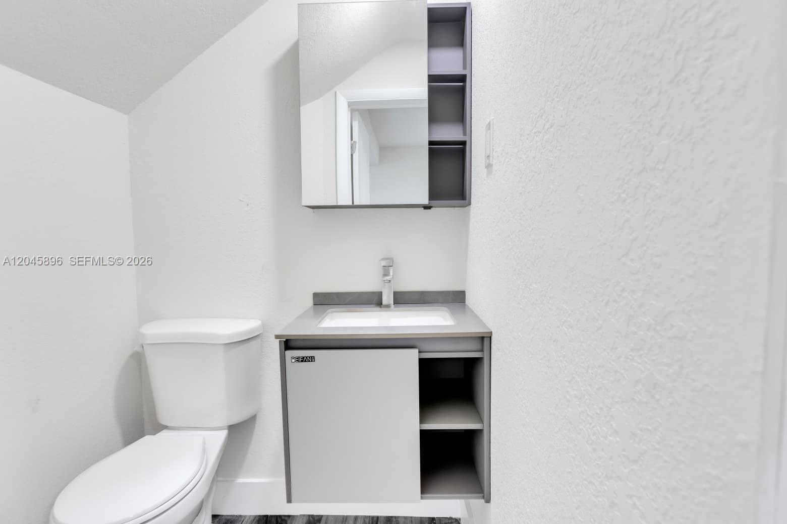A small bathroom features a white toilet, a gray vanity with an open shelf, and a mirrored cabinet — 1430 NW 2nd Ave # 2, Florida City FL 33034, FLORIDA CITY, FL