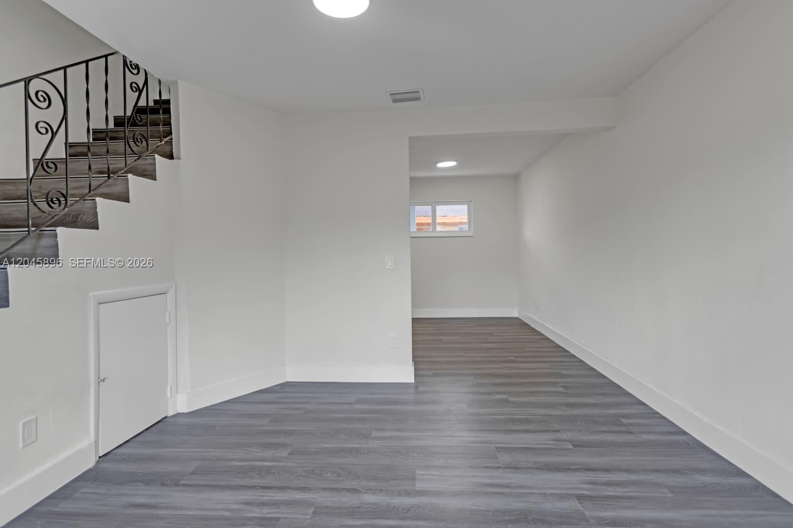 An interior view shows a room with gray wood-look flooring, white walls, and a staircase — 1430 NW 2nd Ave # 2, Florida City FL 33034, FLORIDA CITY, FL