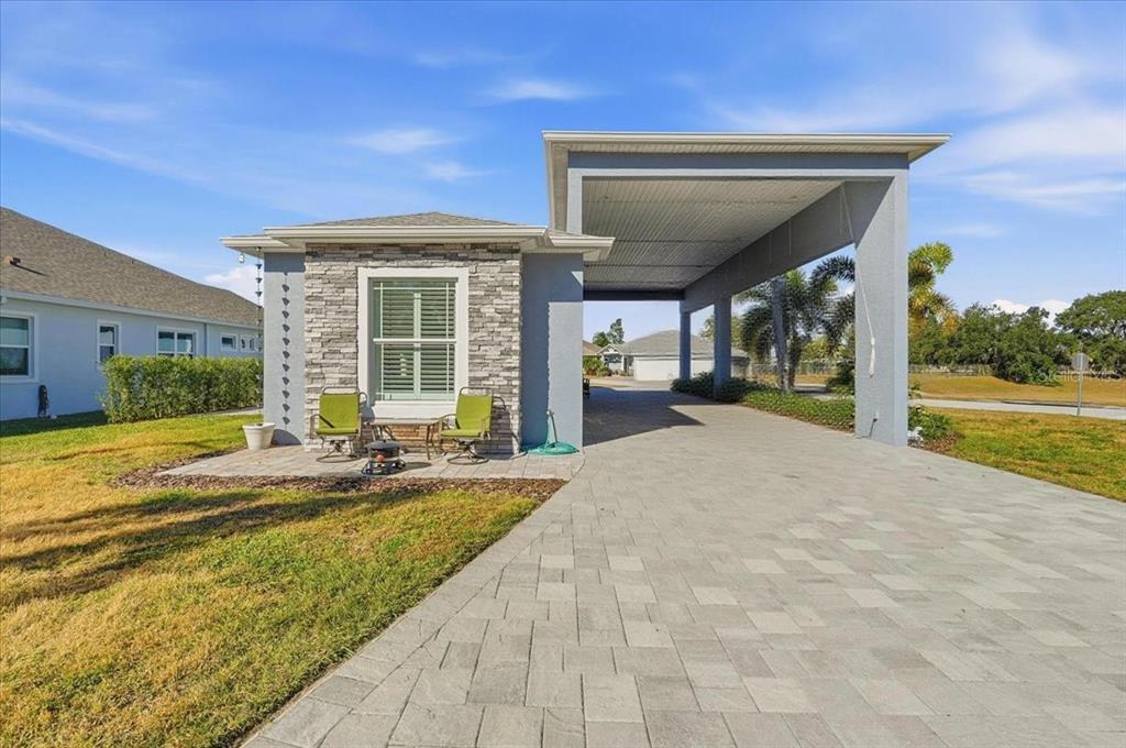 A single-story house exterior features a stone facade, a paved patio, and a large carport — 303 NOLANE LANE, POLK CITY, FL
