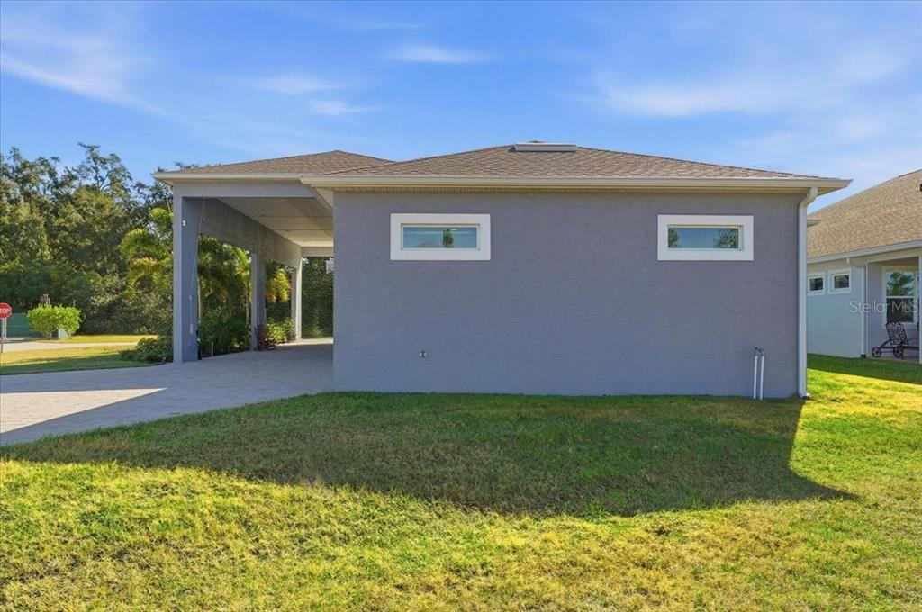 The exterior of a gray house features a covered carport and two small rectangular windows — 303 NOLANE LANE, POLK CITY, FL
