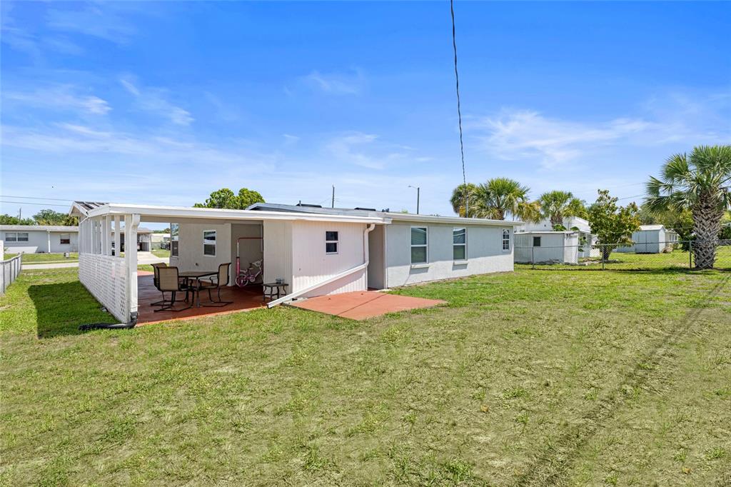 The exterior of a single-story house features a covered patio and a grassy backyard — 8725 AERO AVENUE, NORTH PORT, FL