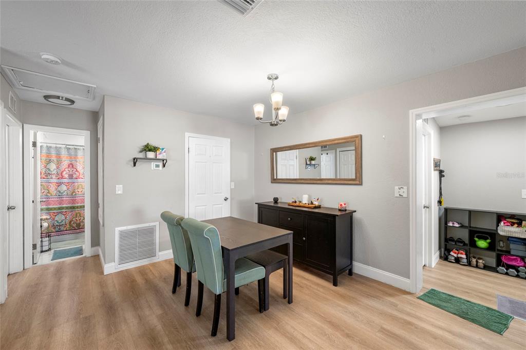 A dining area features light wood flooring, a dark table with chairs, and a sideboard mirror — 8725 AERO AVENUE, NORTH PORT, FL