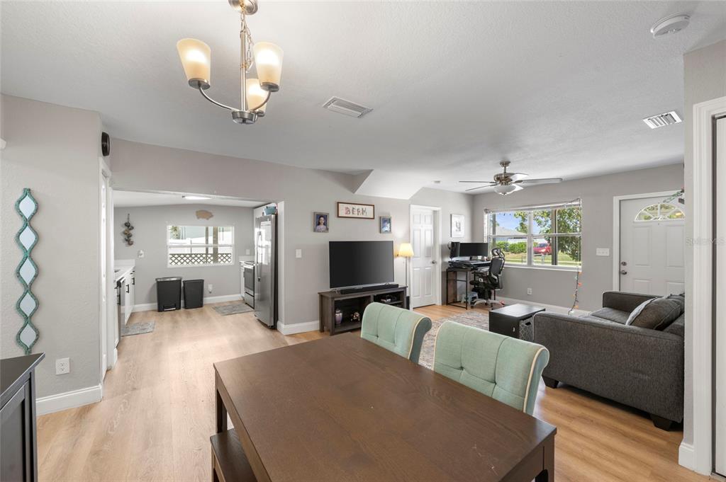 An open-concept living and dining area features light wood flooring, gray walls, and a ceiling fan — 8725 AERO AVENUE, NORTH PORT, FL