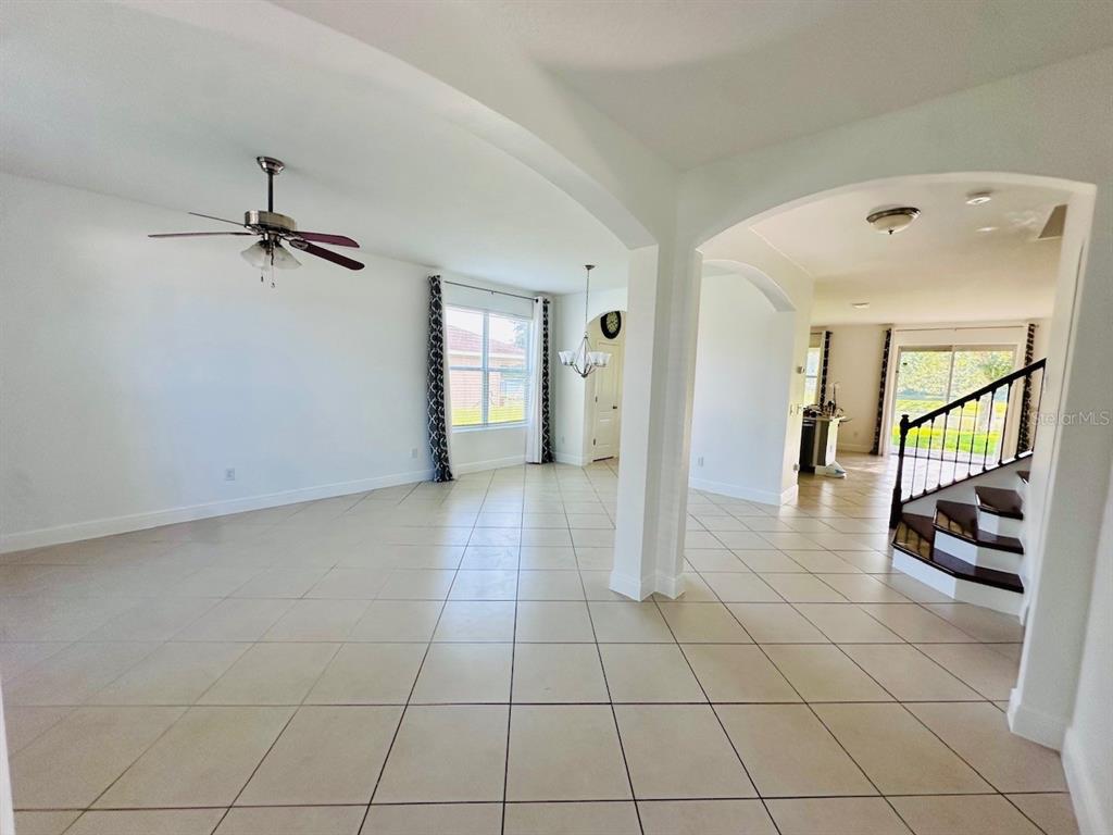 An open-concept living area features light tile flooring, an arched entryway, and a staircase — 10726 CABBAGE TREE LOOP, ORLANDO, FL