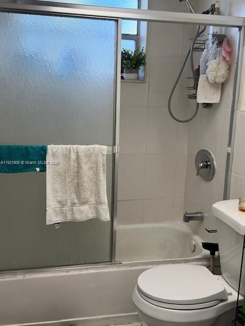 A bathroom features a white bathtub with a sliding glass door and a white toilet — 1370 NE 119th St # 137014, Miami FL 33161, MIAMI, FL