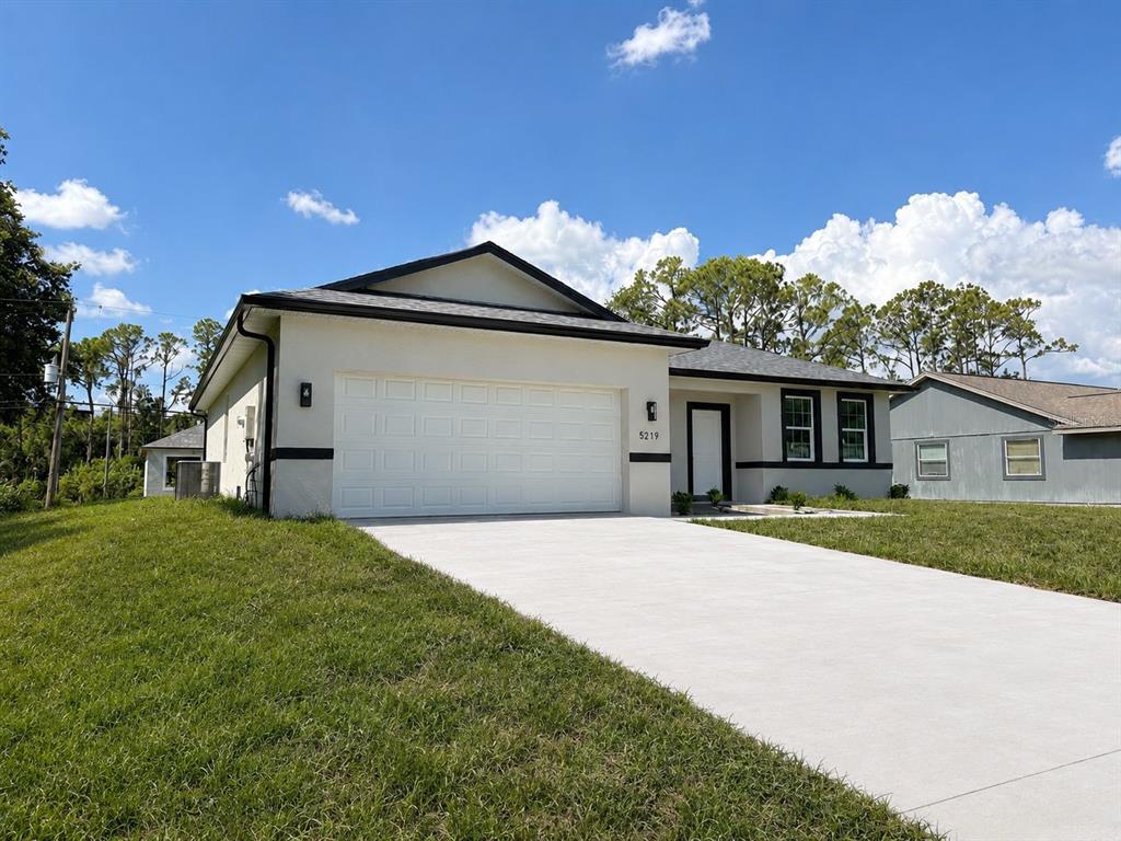A single-story house with a white stucco exterior, black trim, and a concrete driveway — 5219 SYLVANIA AVENUE, NORTH PORT, FL
