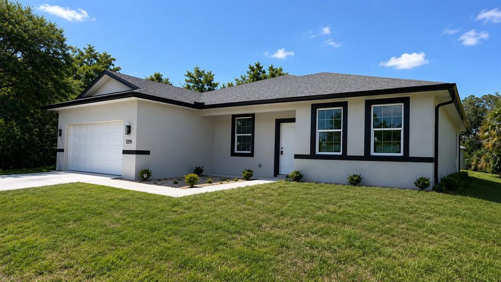 A single-story house with a white stucco exterior, dark trim, and a two-car garage — 5219 SYLVANIA AVENUE, NORTH PORT, FL