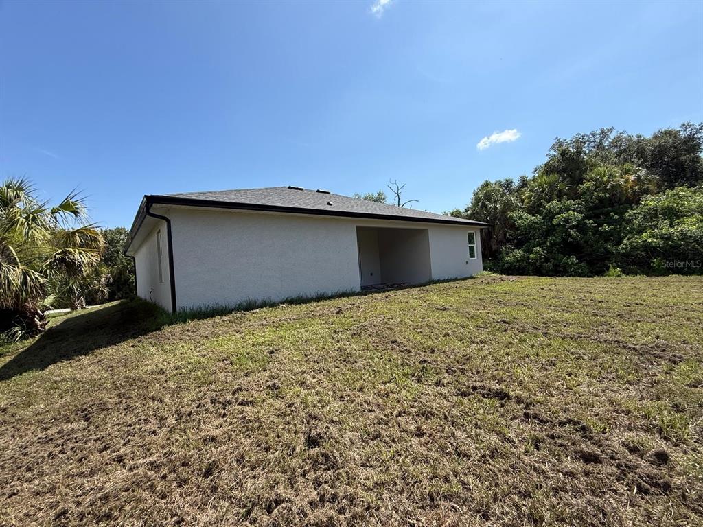 The exterior of a single-story house with a covered patio and a large grassy yard — 5219 SYLVANIA AVENUE, NORTH PORT, FL